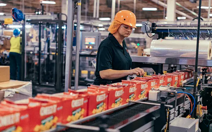woman in protective gear working on cheeze-it production line