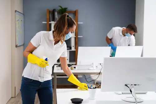 Woman and man in masks cleaning desks