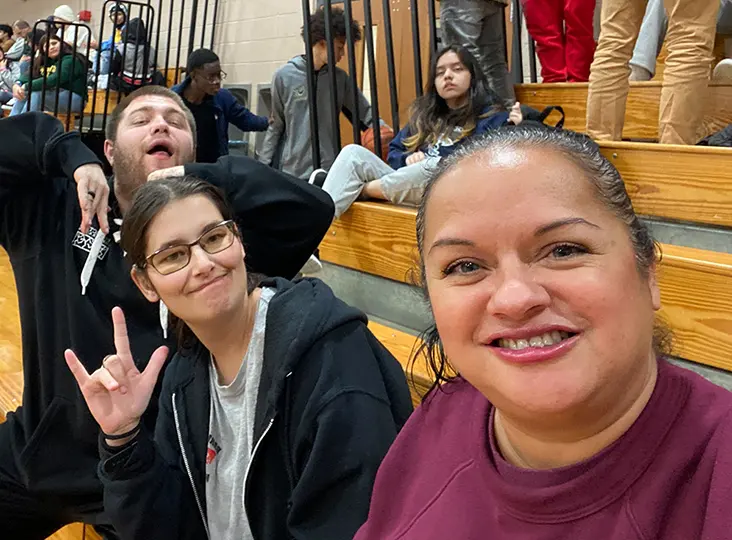 Selfie of two women and a man on gym bleachers