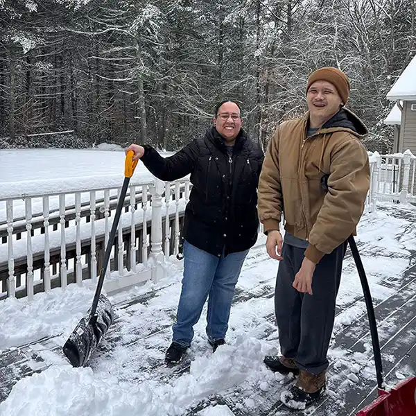 woman and man shoveling snow on a deck take a break for a smile