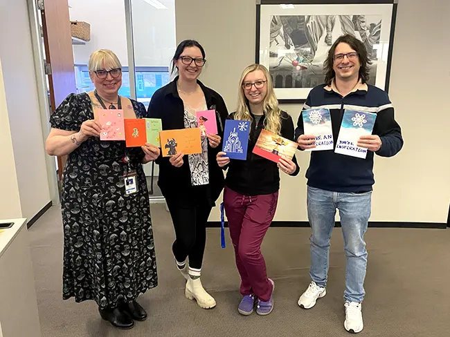 various employees holding home made holiday cards with inspiring messages