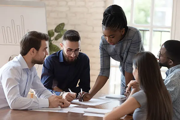 African American woman dressed professionall leads team on conference table