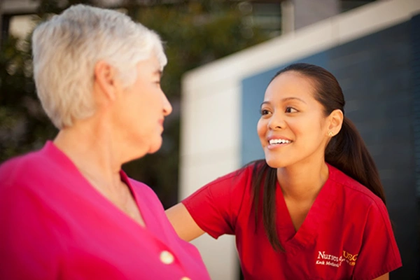 Nurse squatting down to face to face level with a older femail patient